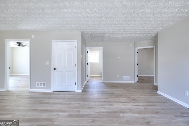 empty room with a textured ceiling and light wood-type flooring