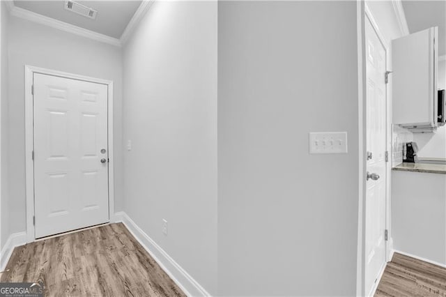 doorway with crown molding and light hardwood / wood-style flooring