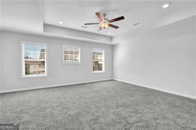 carpeted empty room with ceiling fan and a tray ceiling