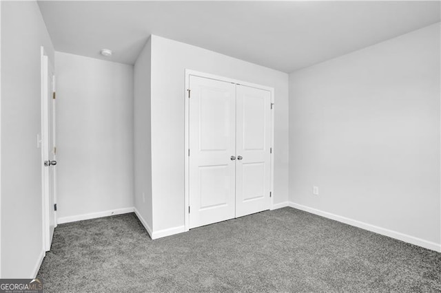 unfurnished bedroom with a closet and dark colored carpet