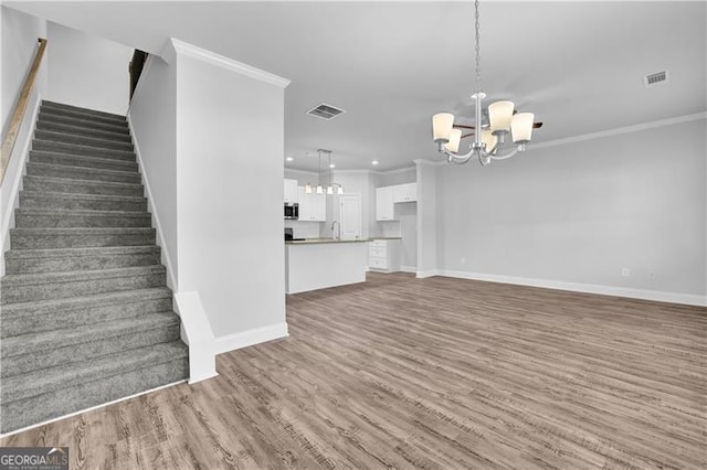 unfurnished living room with dark hardwood / wood-style flooring, crown molding, sink, and an inviting chandelier