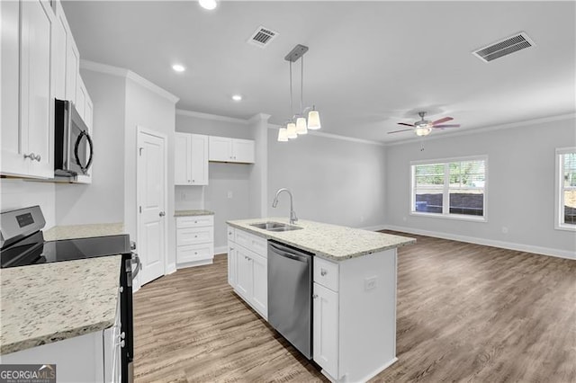 kitchen with appliances with stainless steel finishes, a kitchen island with sink, sink, and white cabinets