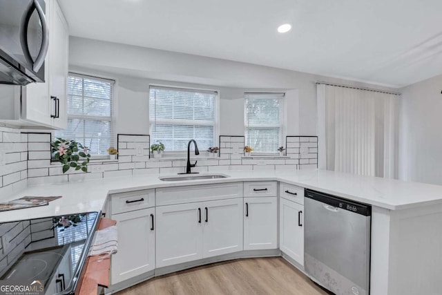 kitchen featuring white cabinetry, dishwasher, sink, kitchen peninsula, and light wood-type flooring