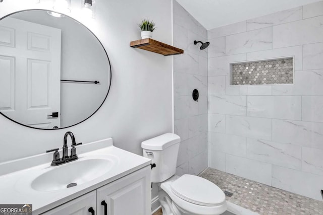 bathroom featuring vanity, toilet, and a tile shower