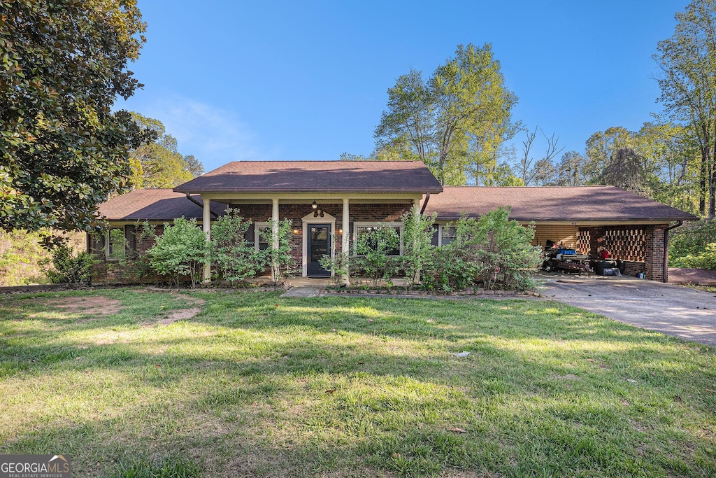 ranch-style home featuring concrete driveway, a front yard, and an attached carport