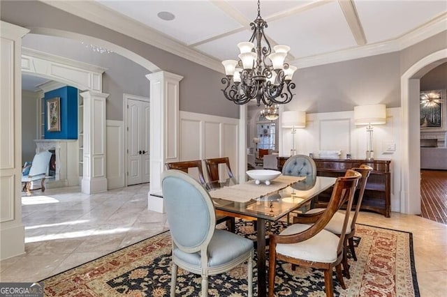 dining space featuring ornate columns, crown molding, light tile patterned floors, and an inviting chandelier