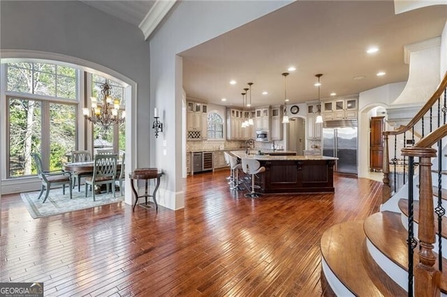 living room with crown molding, beverage cooler, dark hardwood / wood-style flooring, and a notable chandelier