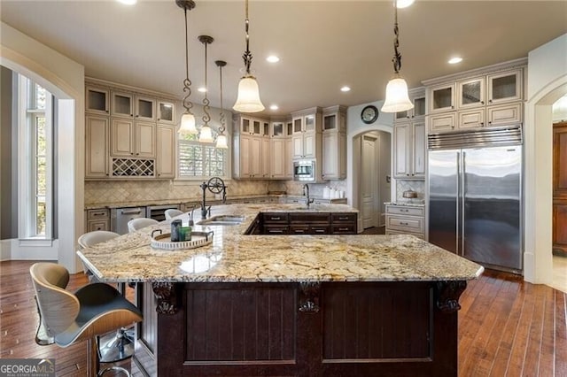 kitchen with hanging light fixtures, built in appliances, and a spacious island