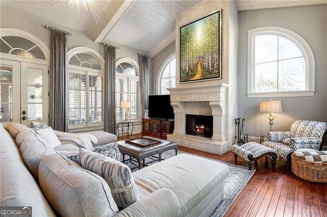 living room with a tiled fireplace, hardwood / wood-style floors, beam ceiling, and plenty of natural light