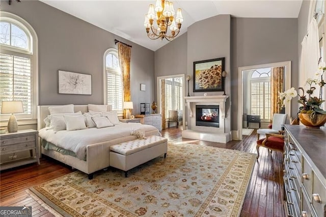 bedroom with dark wood-type flooring, high vaulted ceiling, and a chandelier