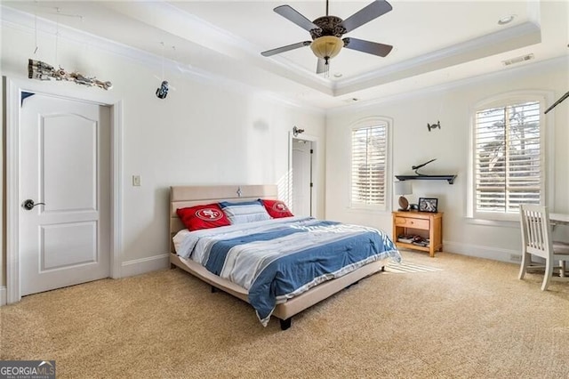 carpeted bedroom with a raised ceiling, crown molding, ceiling fan, and multiple windows