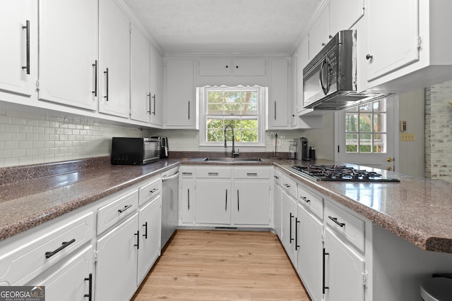 kitchen featuring sink, white cabinetry, stainless steel appliances, kitchen peninsula, and light wood-type flooring