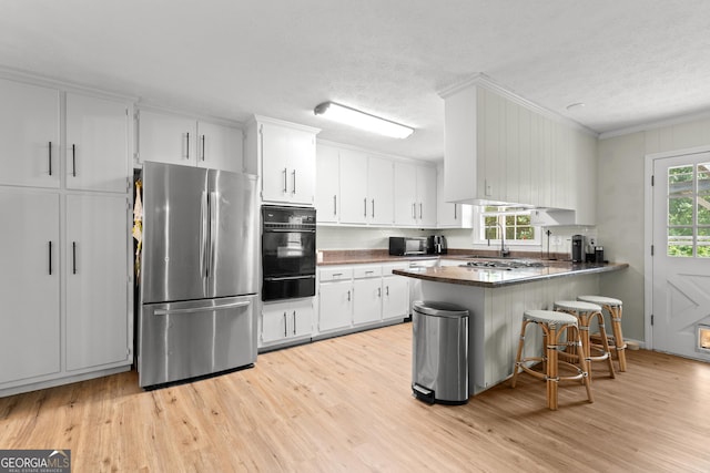 kitchen with white cabinetry, kitchen peninsula, light wood-type flooring, and black appliances