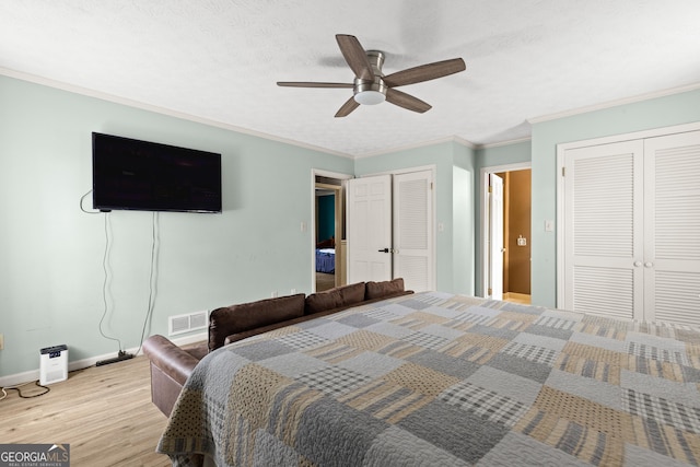 bedroom featuring a textured ceiling, multiple closets, ornamental molding, ceiling fan, and light hardwood / wood-style floors