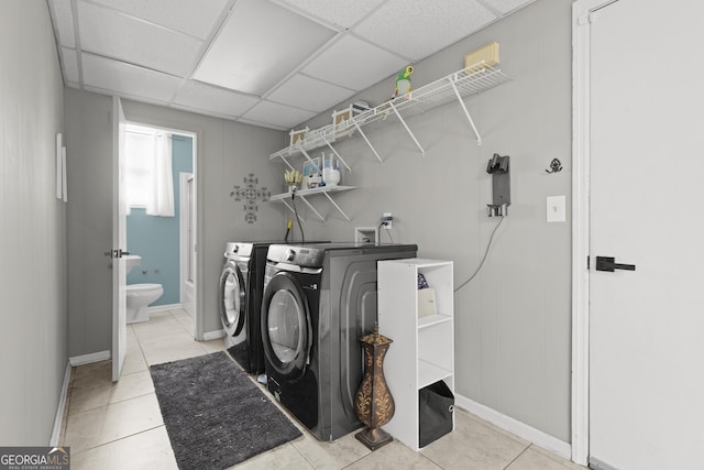 laundry area with washing machine and dryer and light tile patterned floors