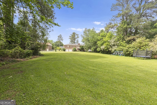 view of yard with a trampoline and a playground