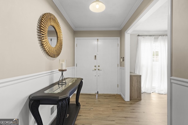 entryway with crown molding and light hardwood / wood-style floors