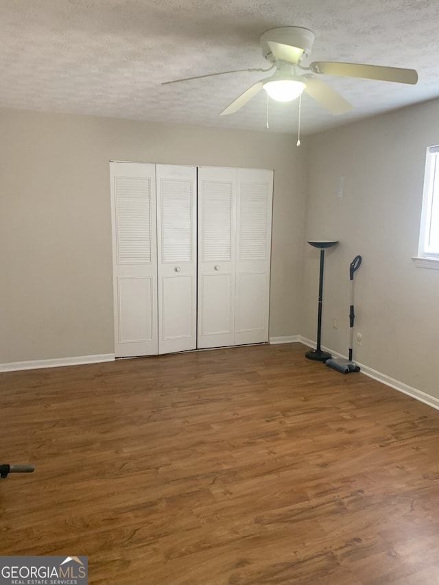 unfurnished bedroom featuring hardwood / wood-style flooring, ceiling fan, a closet, and a textured ceiling