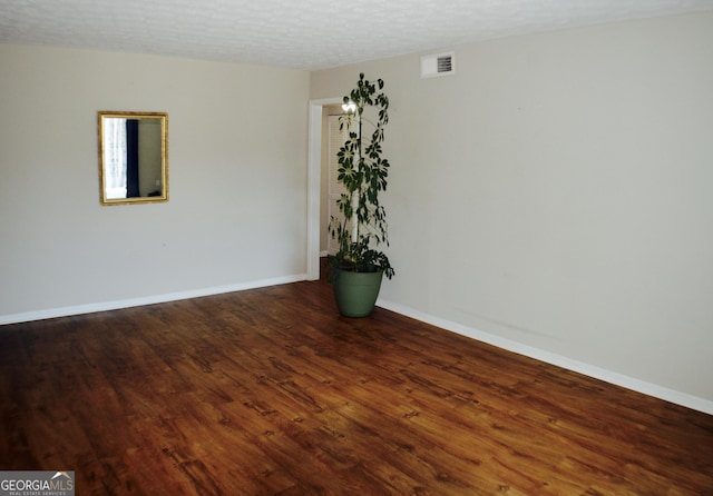 empty room with wood-type flooring and a textured ceiling