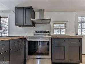 kitchen with wall chimney range hood, stainless steel electric stove, and hardwood / wood-style floors