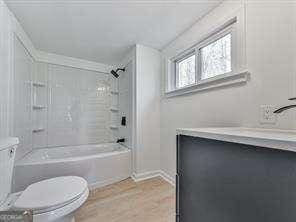 full bathroom with vanity, tiled shower / bath, wood-type flooring, and toilet