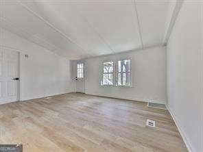 spare room with lofted ceiling and hardwood / wood-style floors