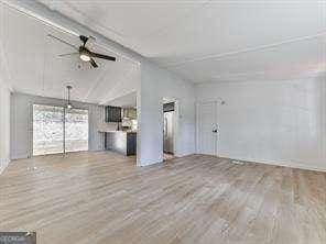 unfurnished living room with hardwood / wood-style floors, vaulted ceiling, and ceiling fan