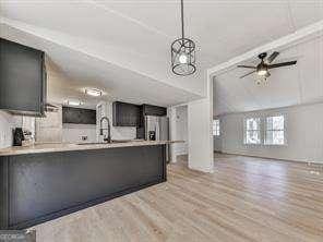 kitchen featuring decorative light fixtures, sink, ceiling fan, stainless steel fridge with ice dispenser, and light hardwood / wood-style floors