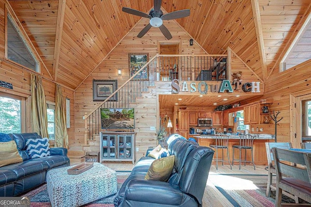 living room with plenty of natural light, wooden walls, high vaulted ceiling, and wooden ceiling