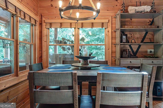 dining area featuring a chandelier and wood walls