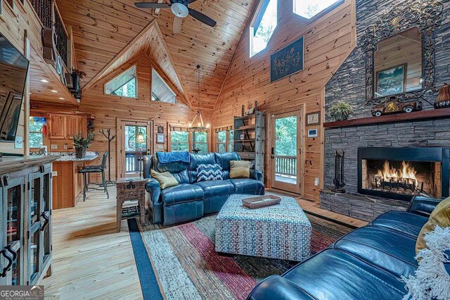 living room with a stone fireplace, wooden walls, wooden ceiling, and hardwood / wood-style flooring