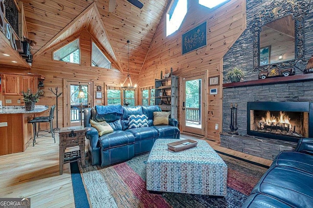 living room featuring wood ceiling, high vaulted ceiling, a fireplace, light wood-type flooring, and wood walls