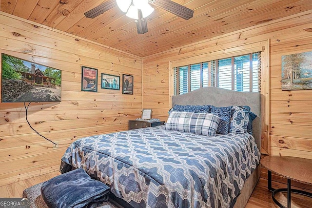 bedroom with a ceiling fan, wooden ceiling, wooden walls, and wood finished floors