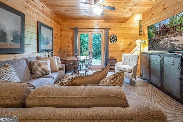 carpeted living room with ceiling fan, wooden ceiling, and wooden walls