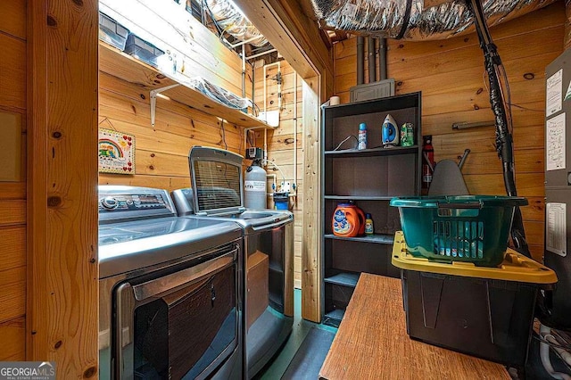 washroom with washer and clothes dryer and wood walls