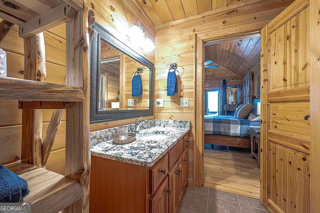 ensuite bathroom with connected bathroom, wood ceiling, tile patterned flooring, vanity, and wood walls