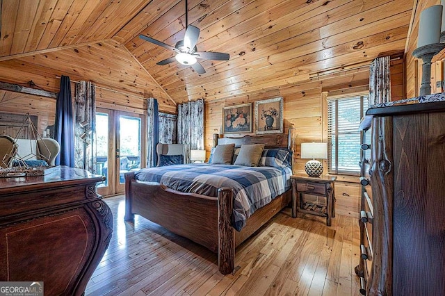 bedroom with access to exterior, light wood finished floors, multiple windows, and wooden walls