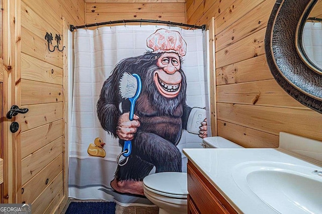 full bathroom with curtained shower, wooden walls, toilet, and vanity