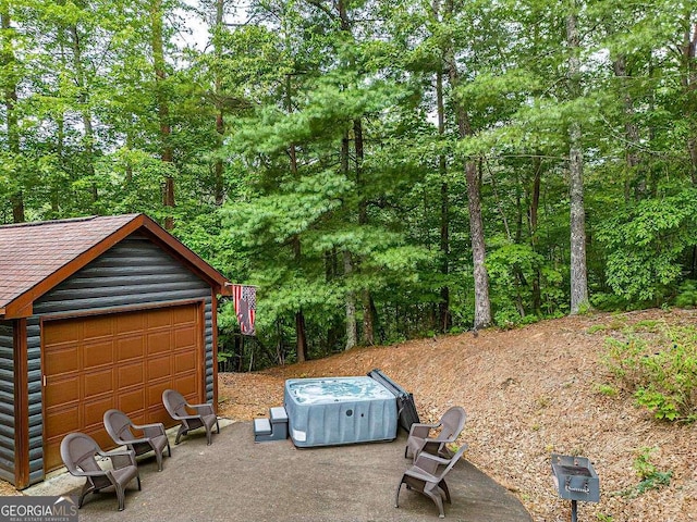 view of yard with a garage, a patio area, and an outbuilding