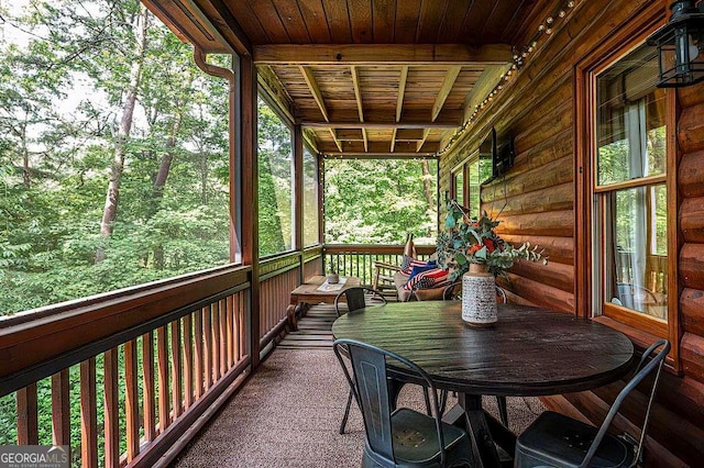 unfurnished sunroom with wood ceiling, beam ceiling, and a wealth of natural light