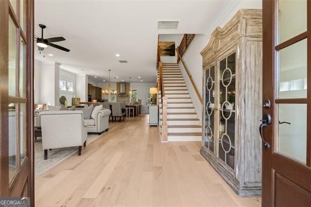 foyer entrance with ceiling fan with notable chandelier and light hardwood / wood-style flooring