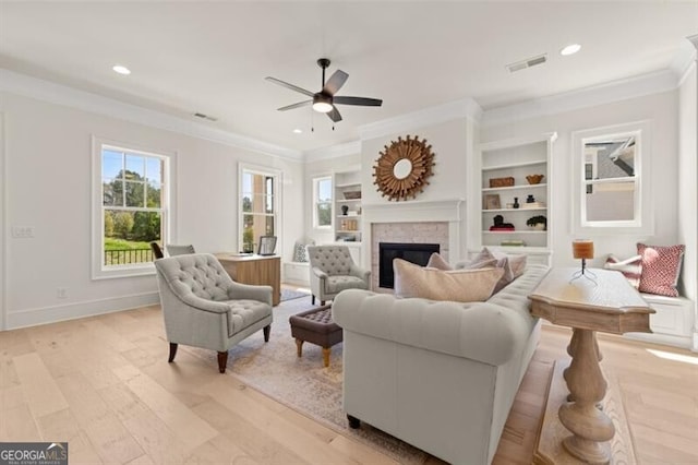 living room featuring crown molding, ceiling fan, built in features, and light wood-type flooring