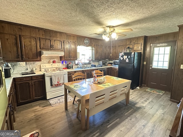 6100 White House Pkwy, Warm Springs, GA 31830 - kitchen featuring light countertops, light wood-type flooring, freestanding refrigerator, under cabinet range hood, and white electric range