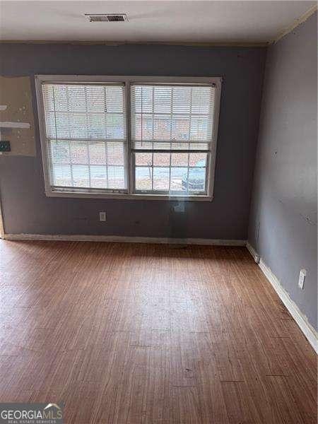 unfurnished room featuring a wealth of natural light and dark wood-type flooring