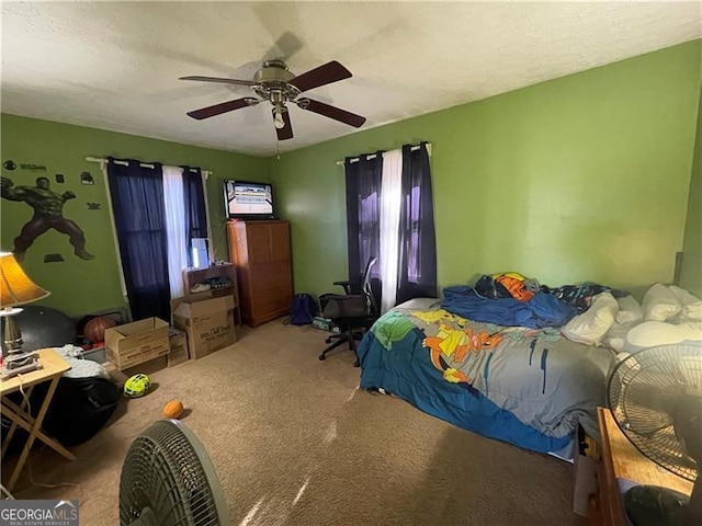 carpeted bedroom featuring ceiling fan, multiple windows, and a textured ceiling