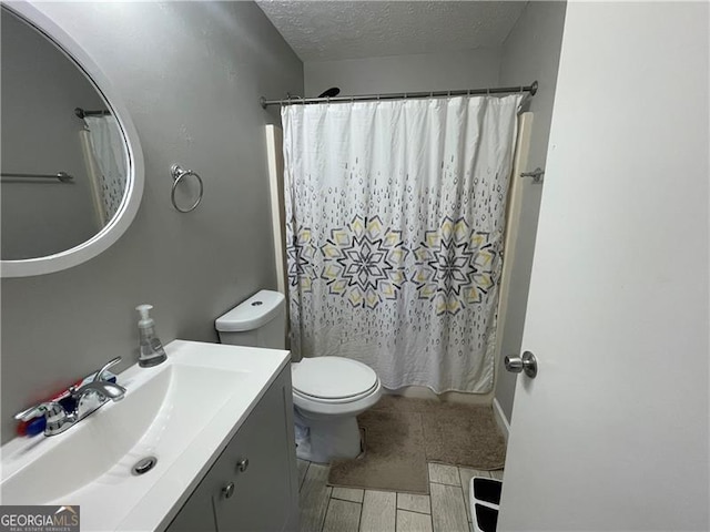 bathroom with vanity, toilet, and a textured ceiling