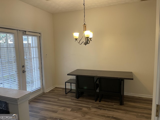 dining space featuring a textured ceiling, dark wood-type flooring, french doors, and a chandelier