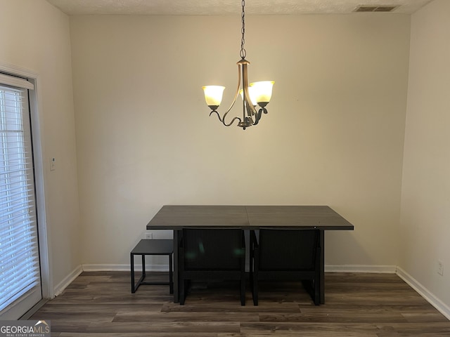 dining space featuring dark hardwood / wood-style flooring, a notable chandelier, and a textured ceiling