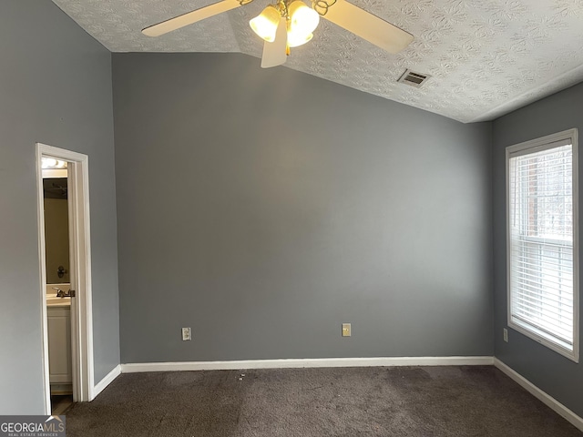 spare room with ceiling fan, a healthy amount of sunlight, dark carpet, and a textured ceiling