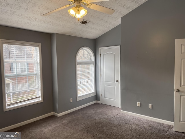 carpeted empty room with ceiling fan, vaulted ceiling, and a textured ceiling